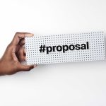 a hand hold a small sign with the words #proposa on it